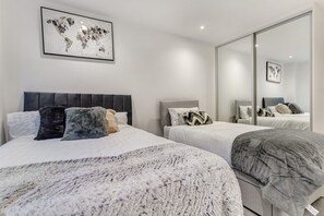 A modern bedroom with two beds, a large mirror, and a world map artwork. - 1 Bed, Sleeps 3, Free Parking, Wifi (Slough)