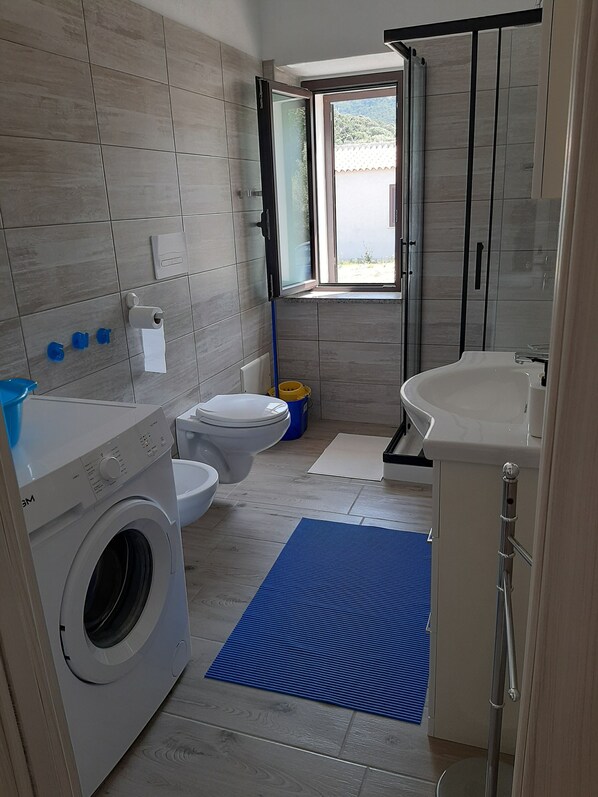 A modern bathroom with a washing machine, toilet, and sink.