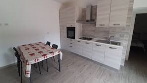 A compact kitchen with a dining area, featuring a table with chairs, a built-in oven, and a sink.