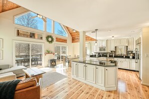 Een ruime keuken met witte kasten, een groot kookeiland en een eethoek met open haard.