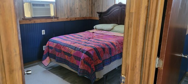 A small bedroom with a bed, a window, and a door.