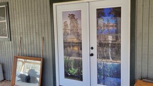 A wooden door with a glass panel, a framed picture on the wall, and a water jug on a table.