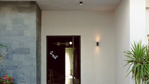 A modern entrance with a glass door, a small outdoor seating area, and a potted plant. - Bird Nest At Sheikh Zayed  (Sheikh Zayed City)