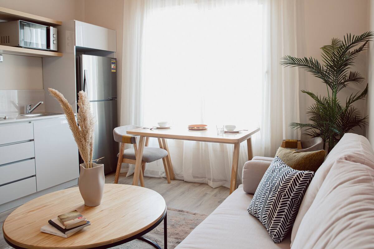 A modern kitchen with a refrigerator, microwave, and a dining area with a table and chairs.