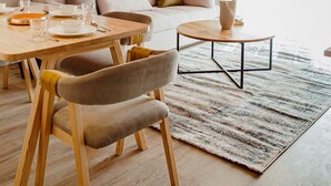 A modern living room with a dining area, featuring a sofa, a coffee table, and a dining table with chairs. - Bird Nest At Sheikh Zayed  (Sheikh Zayed City)