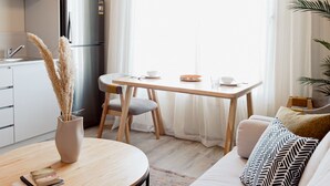 A modern, well-lit living room with a sofa, a round coffee table, and a dining area with a wooden table and chairs. - Bird Nest At Sheikh Zayed  (Sheikh Zayed City)