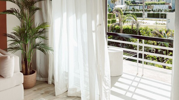 A modern living room with a large sliding glass door leading to a balcony with a view of a residential area. - Bird Nest At Sheikh Zayed  (Sheikh Zayed City)