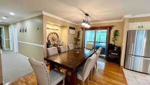 A dining area with a wooden table, four upholstered chairs, a chandelier, and a refrigerator. - HillTop Manor-Spacious 6BR+PS5+FirePit+Pool Table (Lake,Ariel)