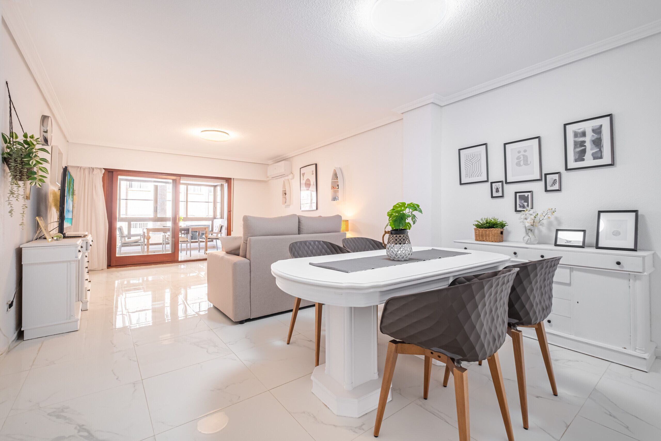 Un salon moderne comprenant un canapé, une table à manger et des chaises. Il y a également un coin cuisine avec des placards et un plan de travail.