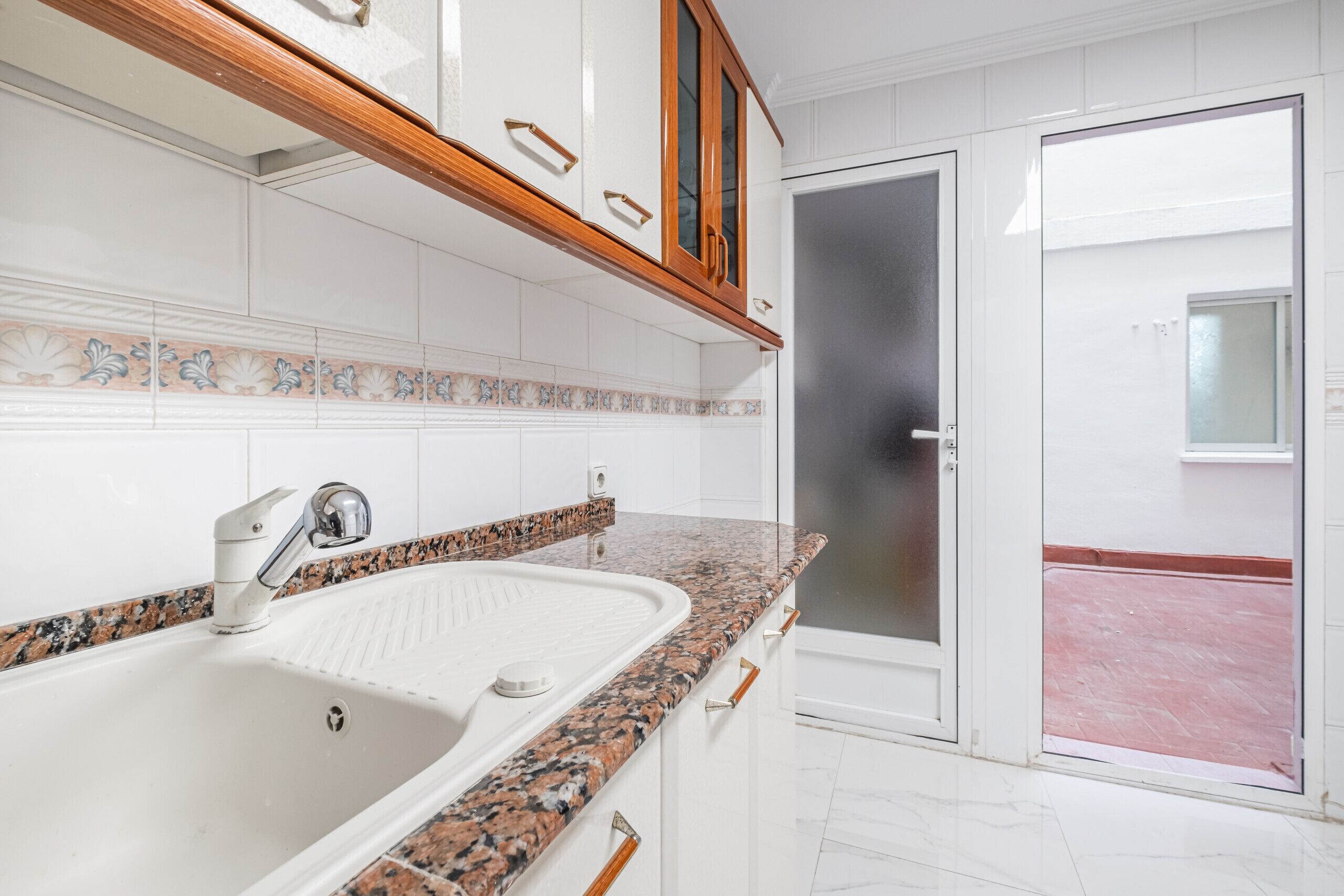 Een moderne keuken met witte kasten, een granieten werkblad en een roestvrijstalen spoelbak.