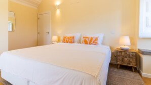 A bedroom with a large bed, two bedside lamps, and a nightstand with a lamp. - CASASUPERTUBOS ÓBIDOS (Obidos)