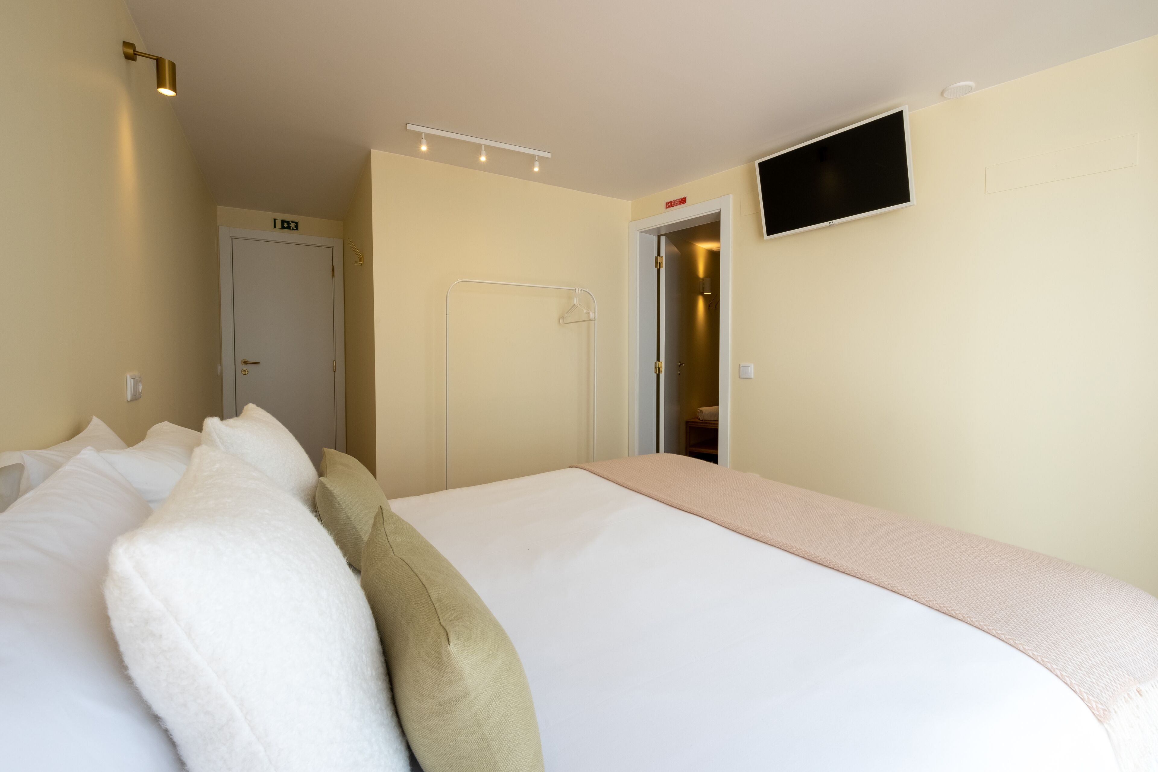 A hotel room with a large bed, a television mounted on the wall, and a door leading to a bathroom.