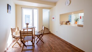 A dining area with a round table and four wooden chairs, a clock on the wall, and a window with natural light. - CASASUPERTUBOS ÓBIDOS (Obidos)