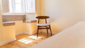 Une pièce d’angle avec une chaise en bois, une fenêtre et une étagère intégrée.