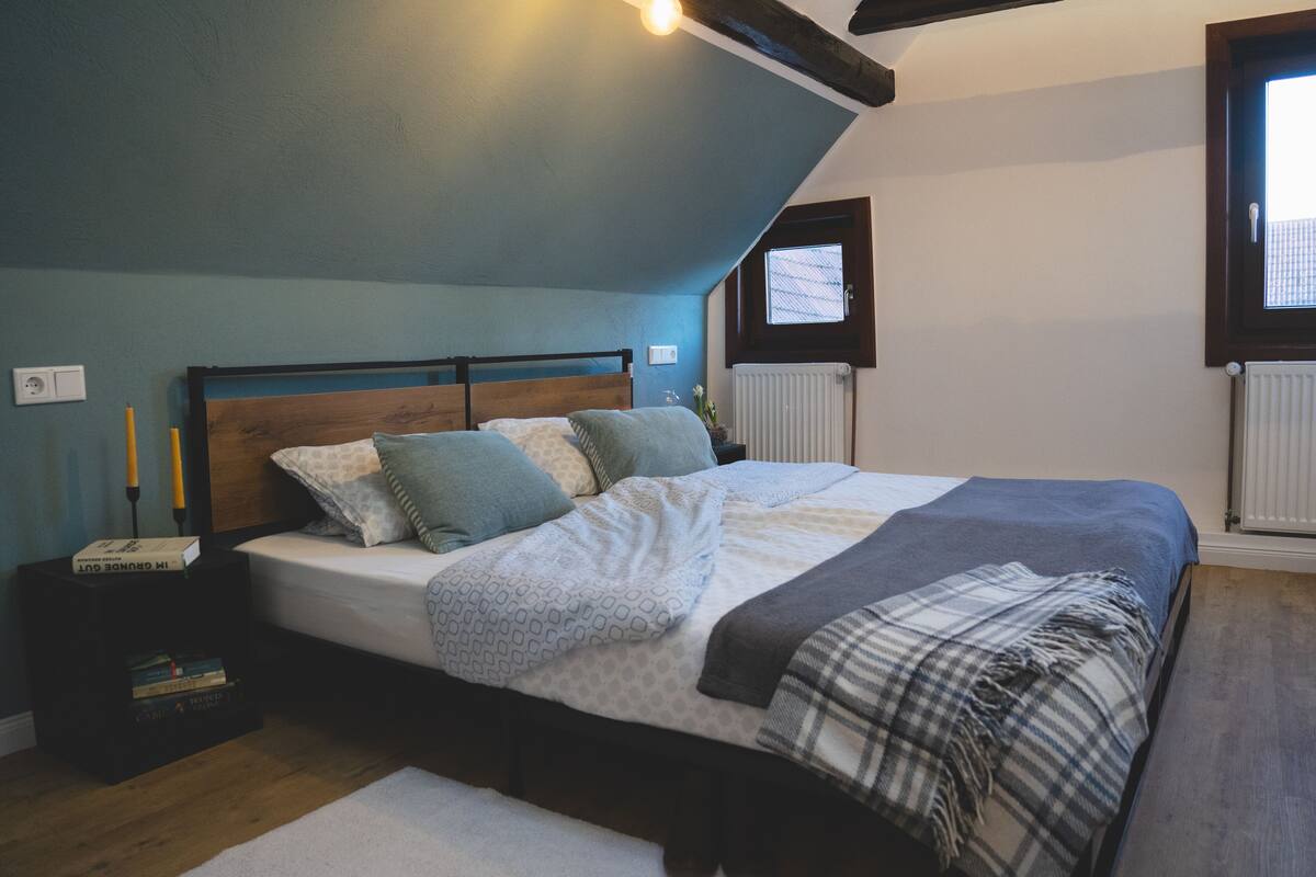 A bedroom with a bed, bedside tables, a window, and a radiator.
