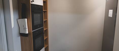 A kitchen with a built-in oven and a refrigerator.