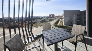 A balcony with a table and two chairs, overlooking a road and buildings. - Ferienwohnung Tamar - 6 Personen, 2 Schlafzimmer, Balkon (Umag)