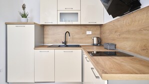 A modern kitchen with a wooden countertop, a sink, a kettle, and a microwave. - Ferienwohnung Tamar - 6 Personen, 2 Schlafzimmer, Balkon (Umag)