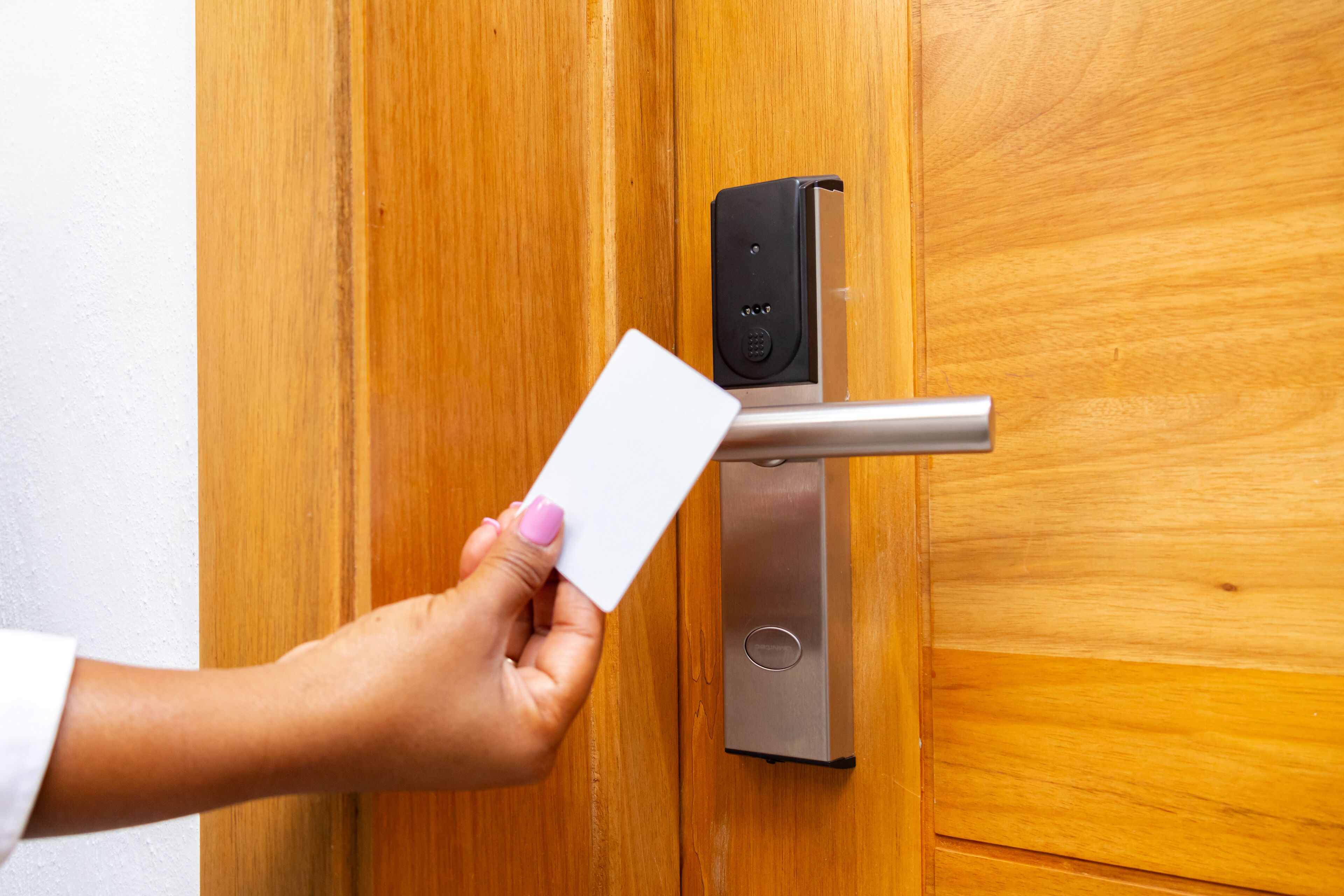 Une main tenant une carte près d’une porte dotée d’un système de verrouillage numérique.