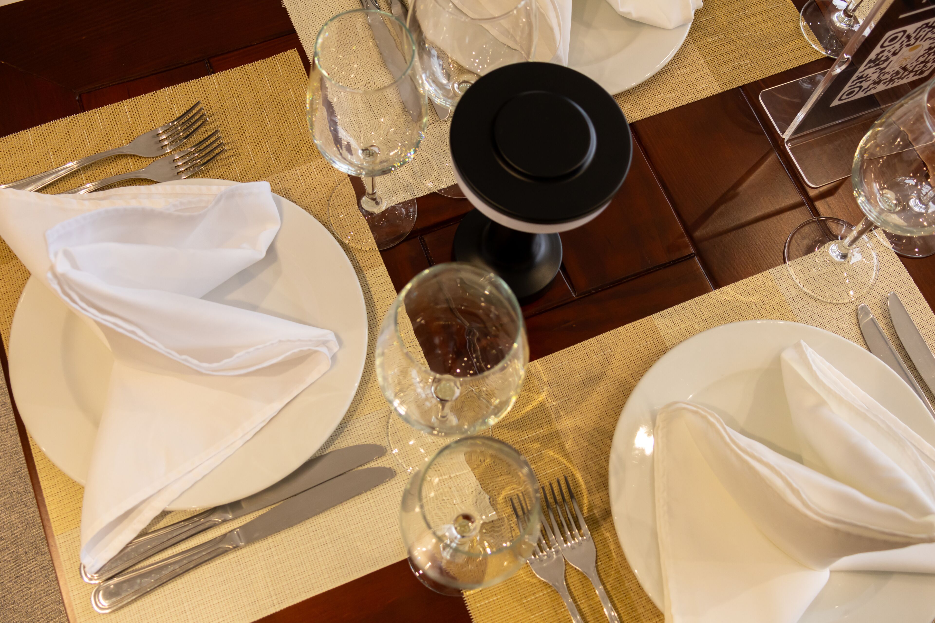 Una mesa de comedor bien puesta, con platos, cubiertos y vasos.