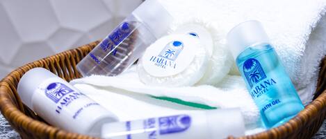 A wicker basket containing toiletries including a bottle of shampoo, a bar of soap, a towel, and a bottle of bath gel.