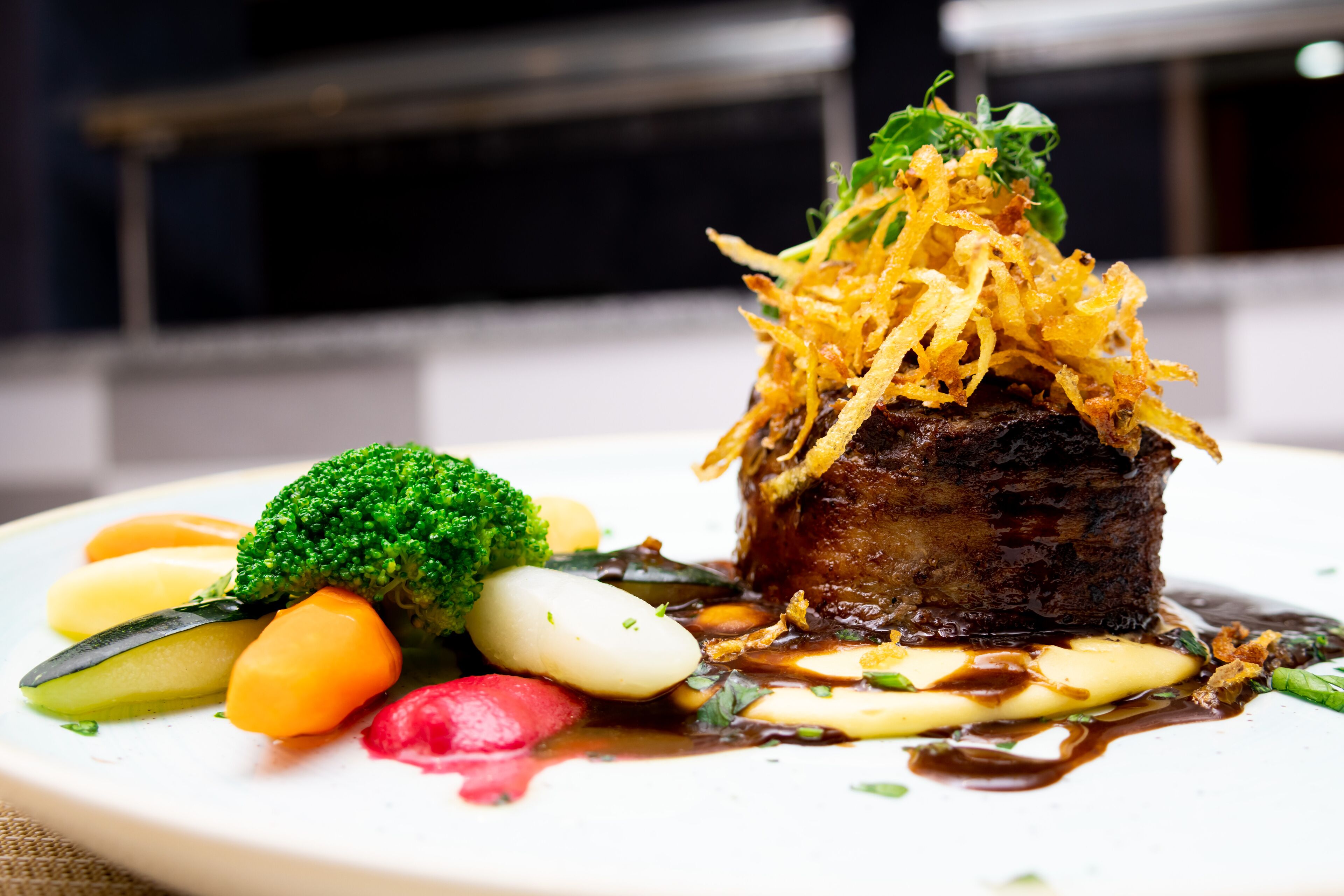 A plate of food with a steak, vegetables, and sauce.