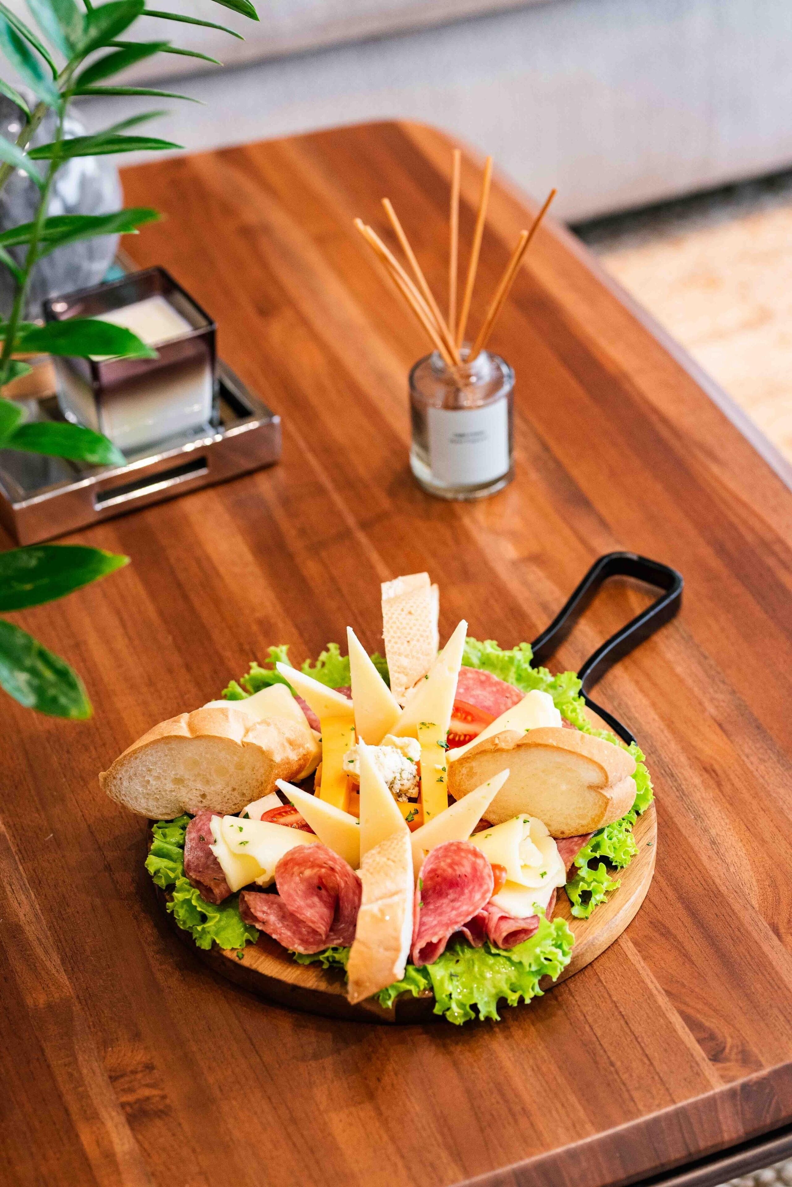 A wooden board with a sandwich and a small candle holder.