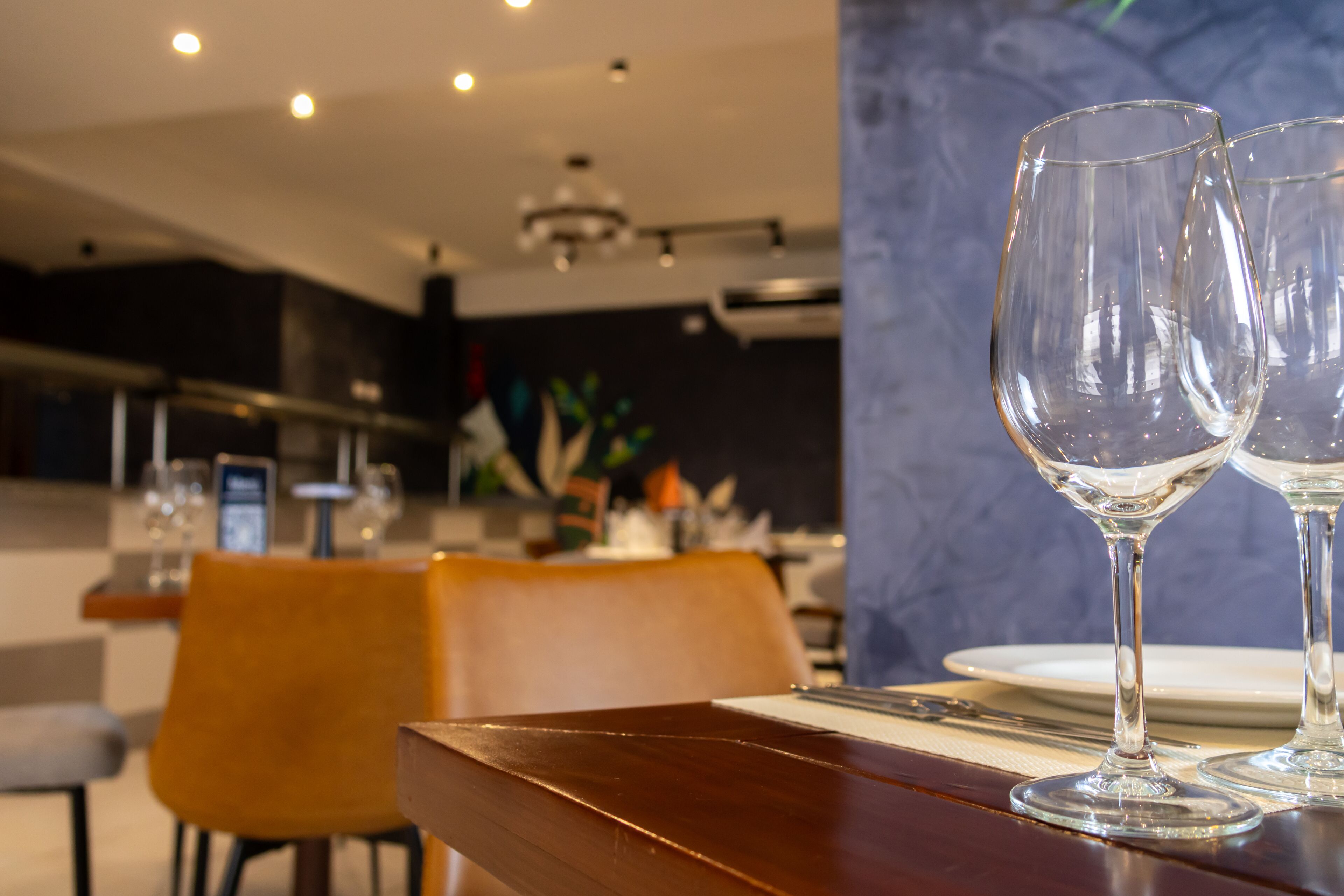 Un comedor con una mesa de madera, dos copas de vino transparentes y un diseño interior moderno.