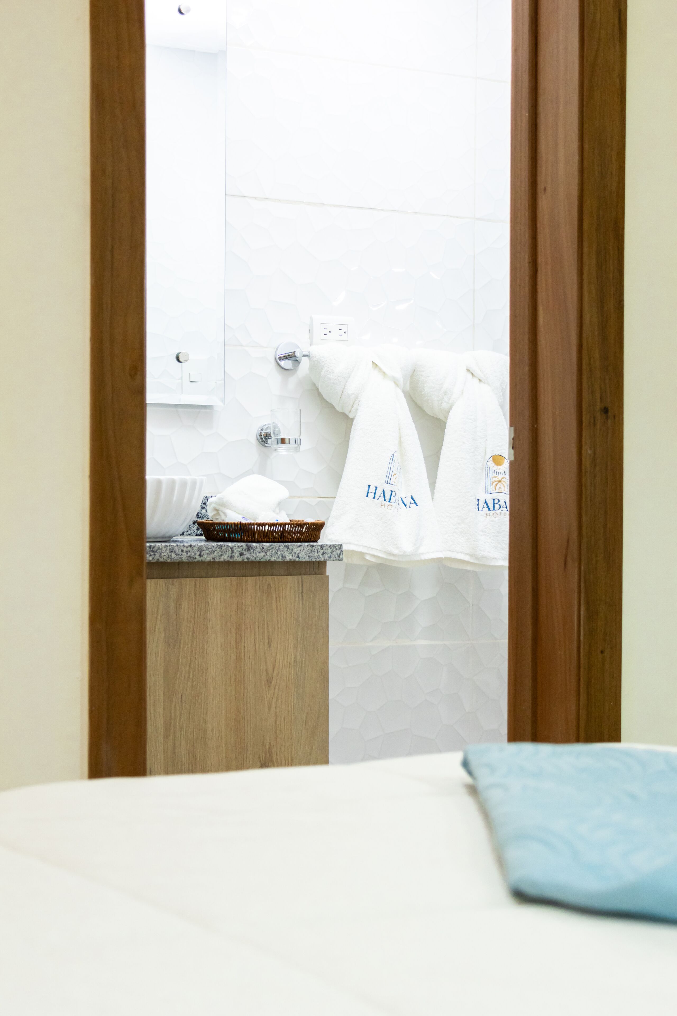 A bathroom with a wooden vanity, a white sink, and a towel rack with towels.