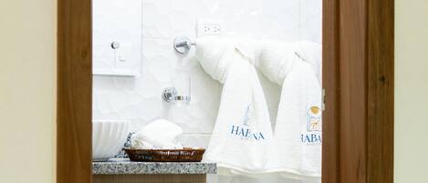 A bathroom with a wooden vanity, a white sink, and a towel rack with towels.