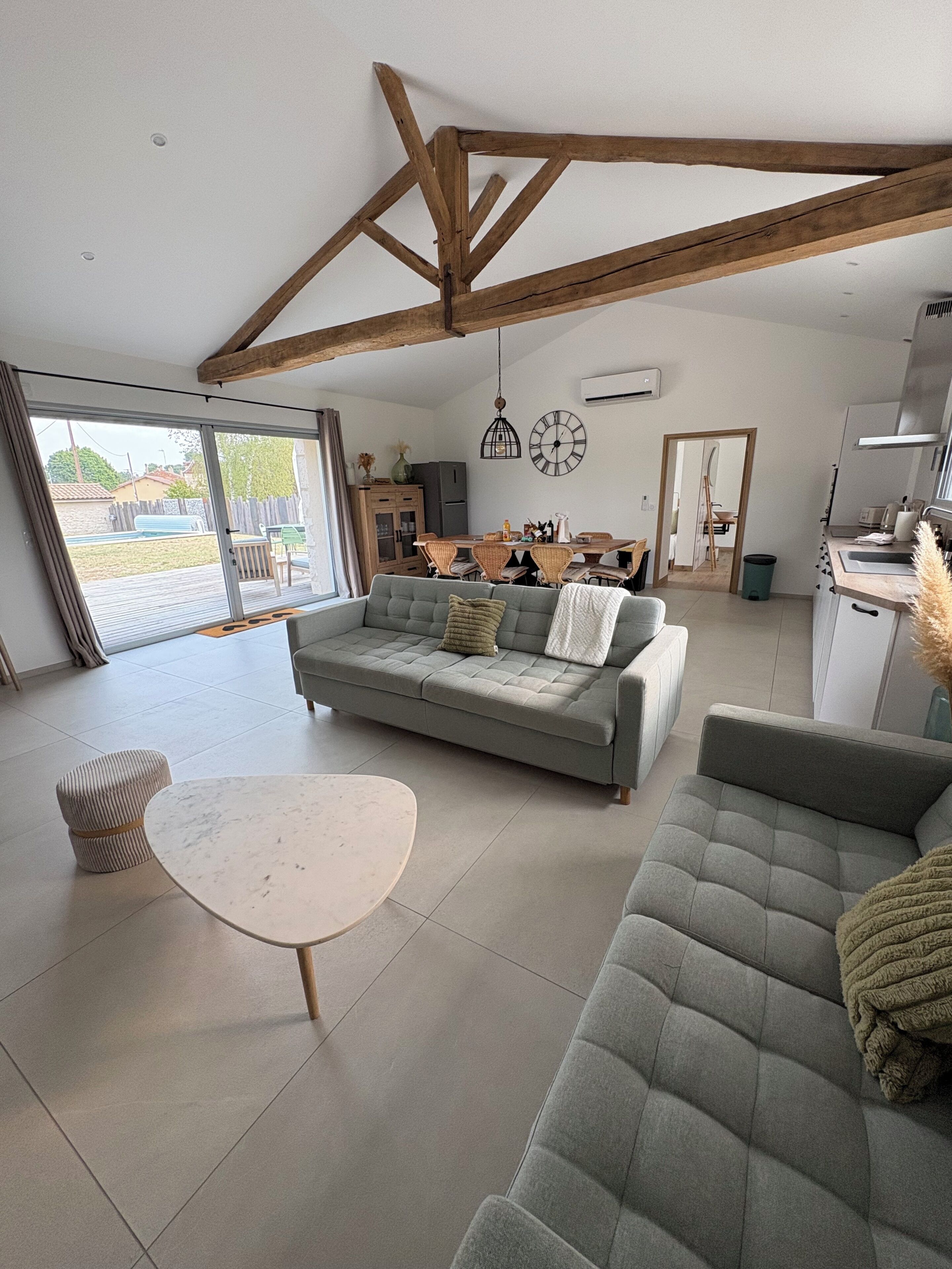 A modern living room with a sofa, a round table, and a dining area with chairs.