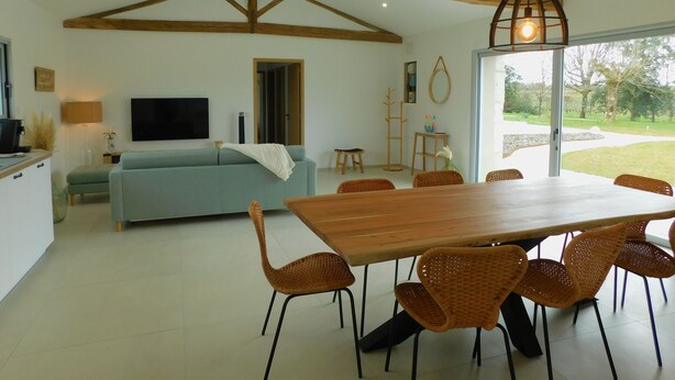 A spacious living area with a large wooden dining table surrounded by wicker chairs, a light blue sofa, and a television mounted on the wall. - Charming cottage with swimming pool in the heart of the Monbazillac vineyard (Monbazillac)