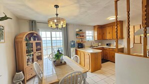 Una cucina con mobili in legno, un tavolo da pranzo con sedie, un lampadario e vista dalla finestra.