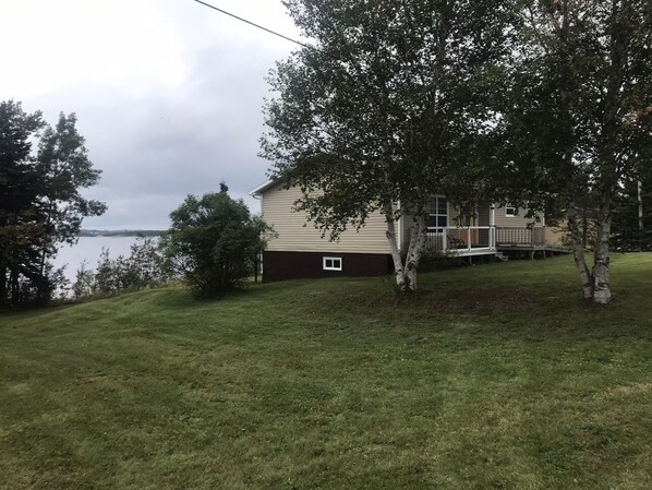 A house with a deck, a small window, and a grassy yard.