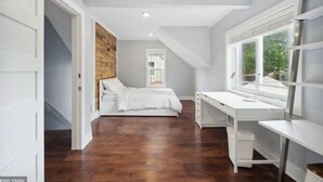 Un dormitorio con cama, escritorio y ventana.