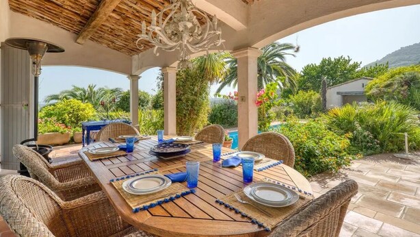 An outdoor dining area with a wooden table set for four, surrounded by wicker chairs, under a wooden pergola with a chandelier. - Peaceful villa (Tourrettes-sur-Loup)