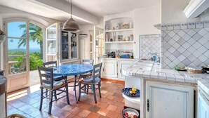 A kitchen with a dining area, open shelving, and a view of the outdoors. - Peaceful villa (Tourrettes-sur-Loup)
