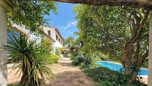 A stone pathway leading to a building with a pool. - Peaceful villa (Tourrettes-sur-Loup)