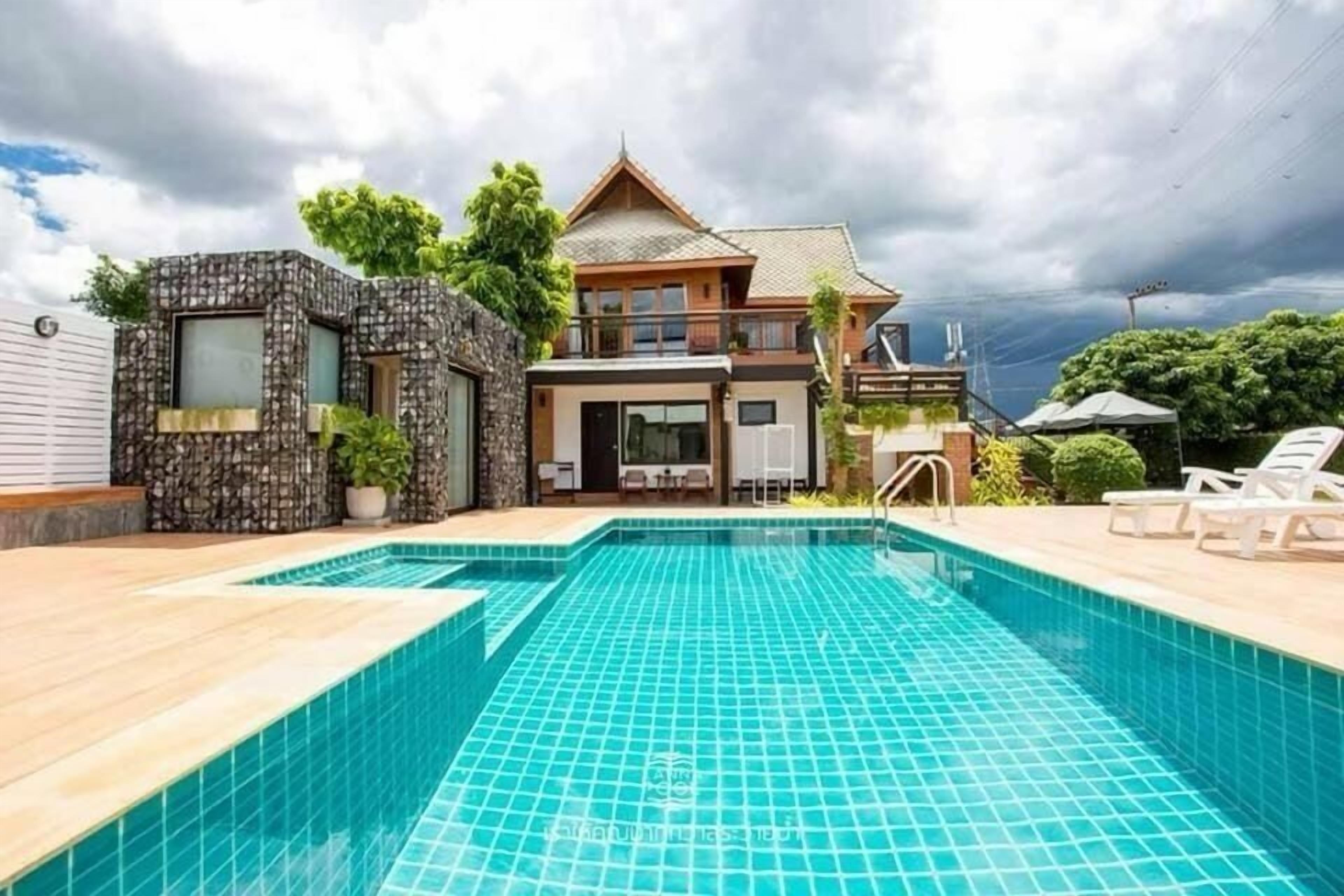 Uma casa de dois andares com piscina na frente.
