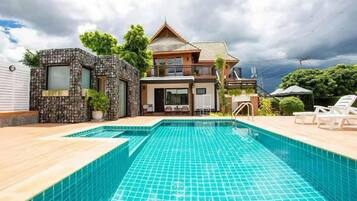 Uma casa de dois andares com piscina na frente.
