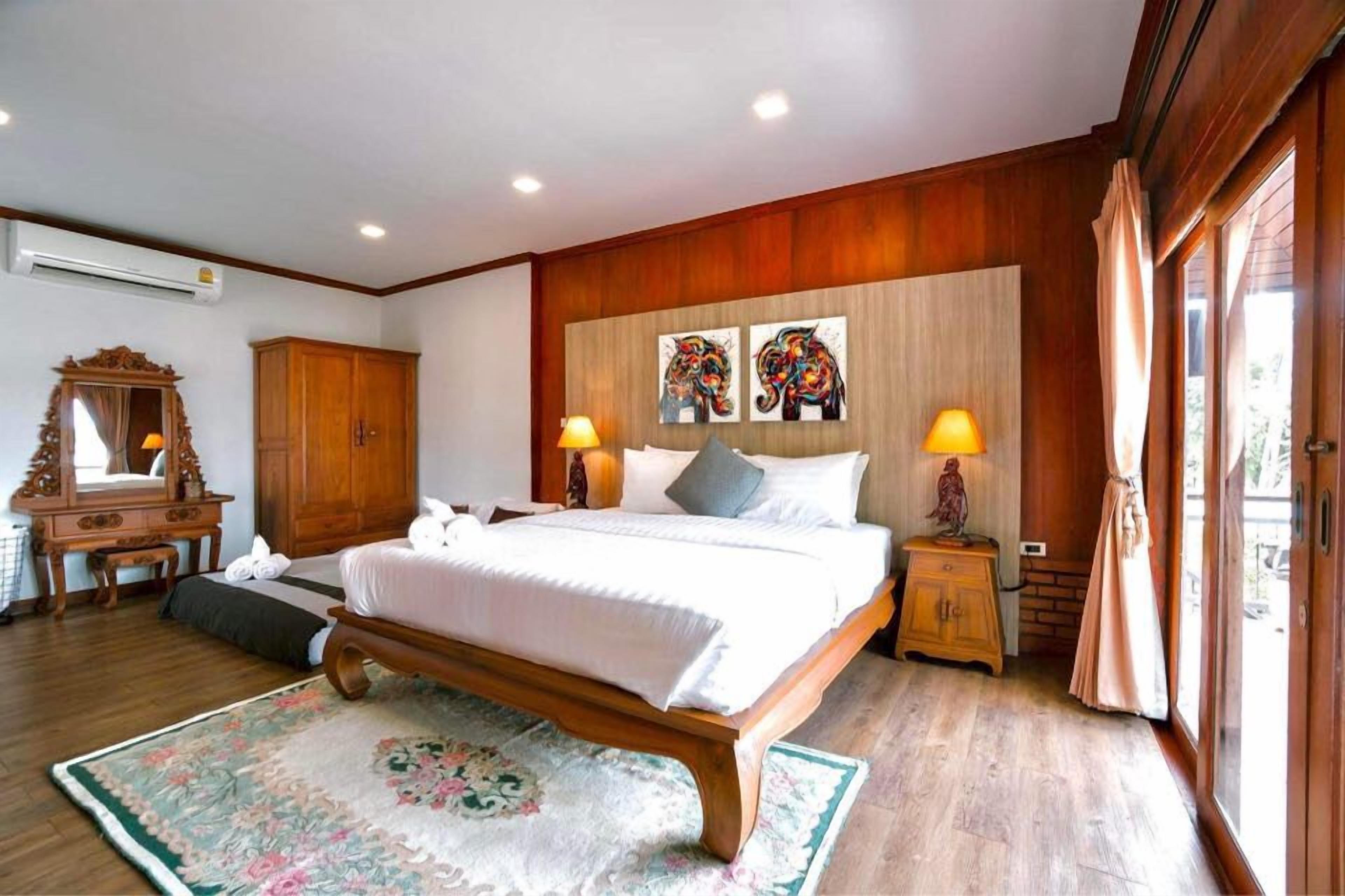 Une chambre à coucher avec un lit en bois, deux lampes de chevet, un miroir, une armoire et des œuvres d’art accrochées au mur.