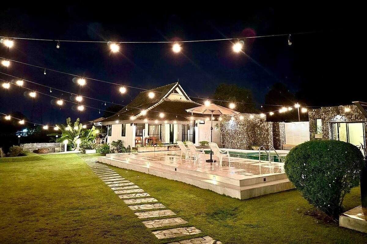 A house with a swimming pool, outdoor seating, and string lights.