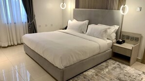 A modern bedroom with a large bed, bedside tables, and a headboard with vertical lines. - Polo Grand Hotel (Maiduguri)