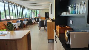 A modern restaurant with a long counter, wooden tables, and chairs. There are large windows along one side, allowing natural light to fill the space. - Polo Grand Hotel (Maiduguri)