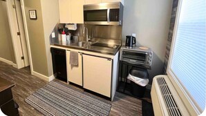 A compact kitchen with stainless steel appliances, a built-in oven, and a small countertop. - Central Farmhouse-Style Micro Apartment (Lethbridge)