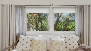 Une chambre à coucher avec un lit, deux fenêtres et des rideaux.