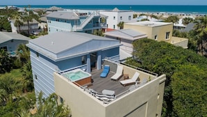 Un bâtiment moderne doté d’une terrasse sur le toit comprenant un jacuzzi, des chaises longues et une piscine.