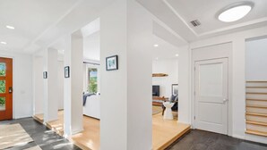 Un intérieur moderne avec un couloir central qui mène à un espace de vie, une cuisine et une chambre.