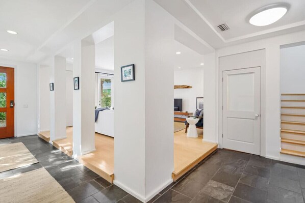 A modern interior with a central hallway leading to a living area, a kitchen, and a bedroom.