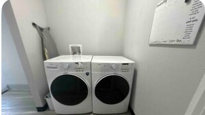 Un área de lavandería con dos lavadoras de carga frontal y un cartel informativo en la pared.